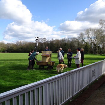 Future Machine and people gathered around on the cricket ground, with blue sky and fluffy clouds above