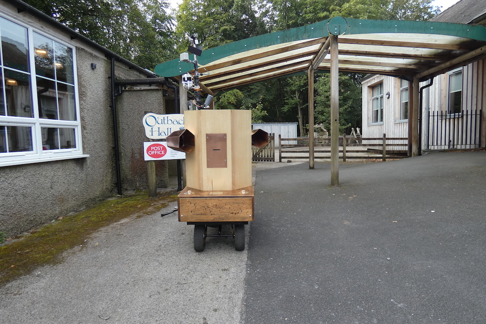 Future Machine in front of a building and two signs one that says Outback Hall and below it one that says 'Post Office'