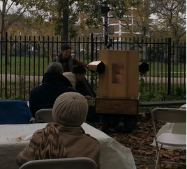 People sitting watching as a child turns the handle on Future Machine's base.