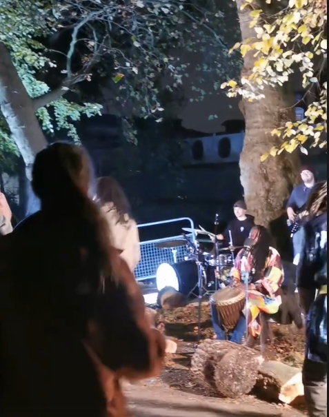 Drummers under a tree with people dancing