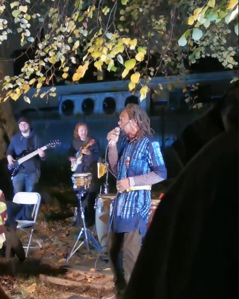 Alex and guitarists under a tree.