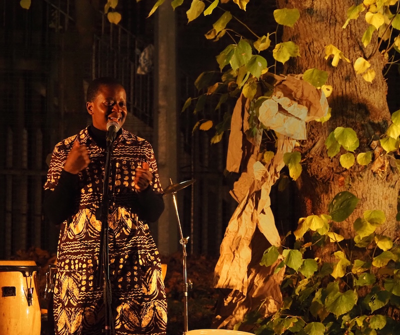 Joelle talking into a microphone in front of a lit up tree.